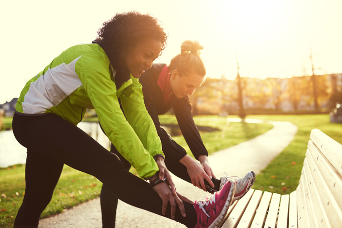 two women stretching for outdoor jog - wellness
