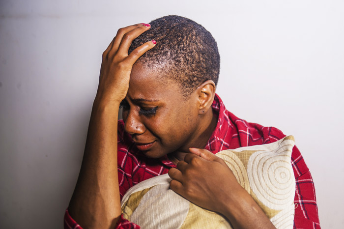 Black woman hugging pillow and crying - depression and substance use
