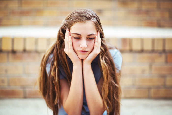 teen girl sitting alone and looking sad