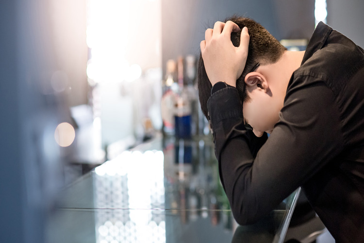 person with head in hands on a bar - alcoholism - alcohol addiction