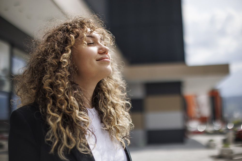 woman outside with her head tilted to the sky